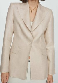 Béžový přizpůsobený blazer s klopovým límcem, zapínáním na jeden knoflík a předními kapsami. Vyroben z texturované tkaniny, strukturovaný střih.