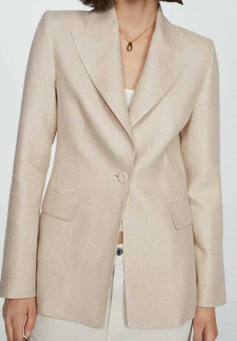 Béžový přizpůsobený blazer s klopovým límcem, zapínáním na jeden knoflík a předními kapsami. Vyroben z texturované tkaniny, strukturovaný střih.