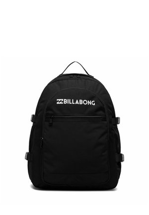 Sac à dos Billabong noir avec poche avant zippée, logo blanc, sangles latérales à boucle et poignée supérieure sur fond blanc.