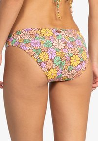 Bas de bikini en tissu marron présentant un motif floral coloré avec des fleurs jaunes, roses et vertes ; style à couverture moyenne avec des bords sans couture.
