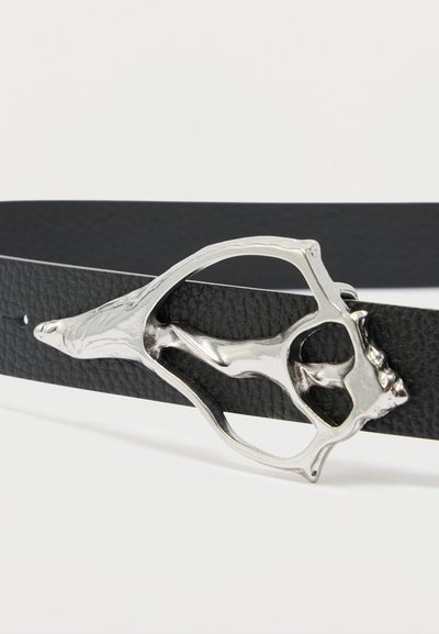 Ceinture en cuir noir texturé avec une boucle argentée en forme de figure humaine allongée, au design abstrait et cadre ouvert.