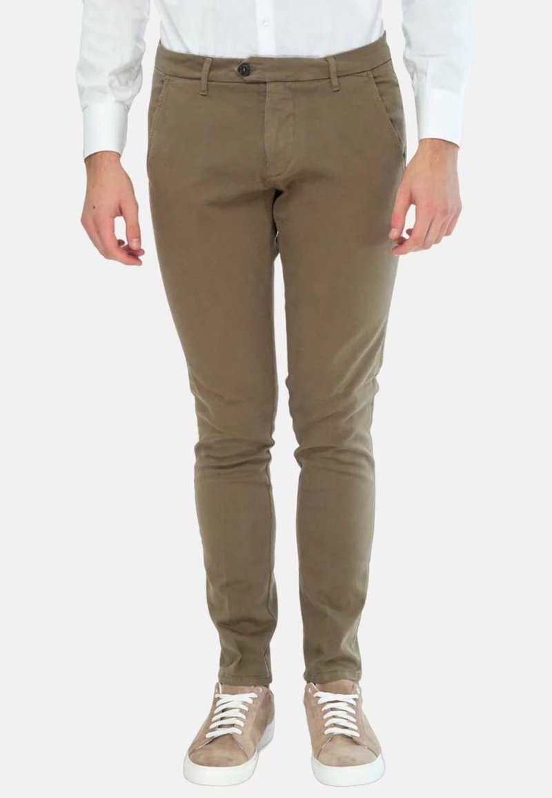 Chinos verde oliva con un design slim fit, realizzati in tessuto misto cotone, dotati di tasche frontali e sneakers marroni con lacci bianchi.