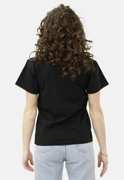 T-shirt nera a maniche corte in cotone, con un classico collo a giro. Il modello indossa jeans azzurri, visto di spalle.
