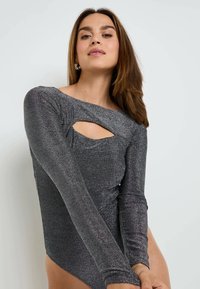 Body a maniche lunghe in materiale grigio scuro scintillante, con scollatura asimmetrica e una apertura a forma di chiave sul petto.