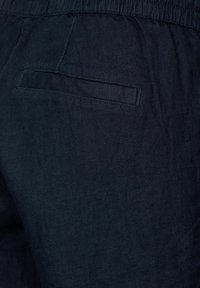 Ciemnoniebieskie lniane spodnie o teksturowanym wykończeniu, z elastycznym pasem w talii i pojedynczą kieszenią z tyłu.