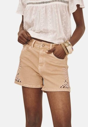 Shorts de mezclilla color arena con recortes florales y bordados en los laterales, con un diseño de cinco bolsillos y cierre de botón.