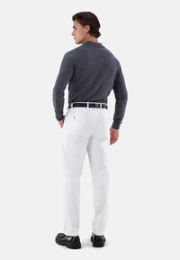 Langärmliges Poloshirt aus Kohlefaser, weiße Hose, schwarzer Gürtel, schwarze Schuhe. Modell von hinten gezeigt, glatter Stoff, maßgeschneiderte Passform, minimalistische Details.