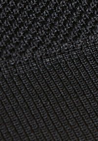Tessuto a maglia nero con due motivi distinti: una sezione superiore texturizzata e una sezione inferiore a costine, entrambe con una finitura uniforme e liscia.
