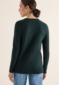 Maglione verde scuro con orlo e polsini a coste, realizzato in tessuto morbido. Il design presenta un collo rotondo e una vestibilità rilassata.