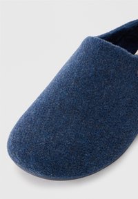 Pantofole in feltro di lana di colore blu scuro con punta arrotondata e suola liscia. Design semplice, che offre una texture morbida e un aspetto accogliente.