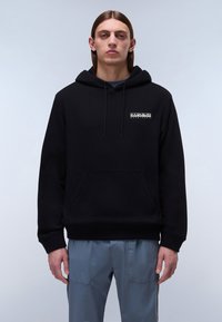 Svart bomullshoodie med en framfickor i kengurustil, dragsko på huvan och en liten vit grafisk logotyp på vänstra bröstområdet.