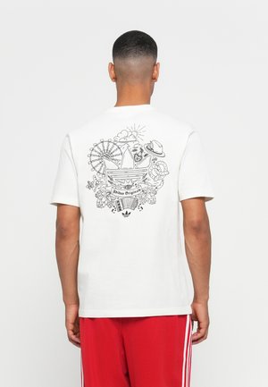 Hvit t-skjorte laget av bomull med svart grafisk trykk på ryggen, inkludert et Adidas-logo og forskjellige morsomme design som et pariserhjul.