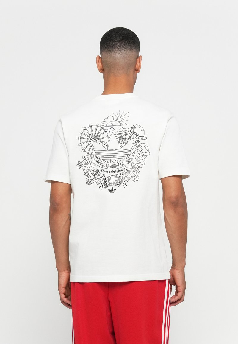 White t-shirt made of cotton featuring a black graphic print on the back, including an Adidas logo and various fun designs like a ferris wheel.