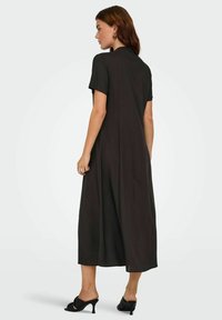 Robe midi noire à manches courtes en tissu lisse ; elle présente une silhouette décontractée avec un détail de couture au dos et un ourlet légèrement évasé.