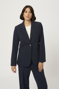 Námořnický blazer s jedním knoflíkem, se špičatými klopami a dvěma bočními kapsami. Vyrobeno z hladkého materiálu, přiléhavý střih.