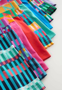 Row of colorful boxer briefs with bold geometric patterns and contrasting waistbands, arranged on a light surface.