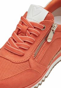 Oranssi mokkanahkainen sneaker, jossa on reikäkuviointi, valkoiset yksityiskohdat, yhteensopivat nauhat ja toimiva sivuvetoketju. Valkoinen kumipohja, jossa on tekstuuriset yksityiskohdat.