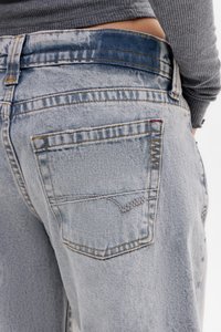 Svetlo modri jeans z ravnim krojem, ki imajo eno zadnjo žepek z dekorativnim šivom in zbledel pas.