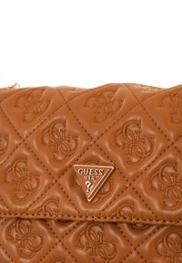 Borsa a tracolla sintetica marrone trapuntata con modelli embossati, una piastra logo metallica triangolare e dettagli di cucitura visibili.