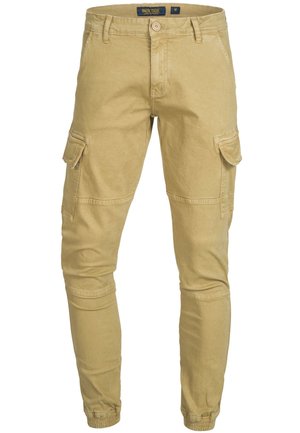 Pantalones cargo de color beige claro con corte ajustado, fabricados en algodón. Presenta múltiples bolsillos, cierre de botón y puños elásticos en los tobillos.