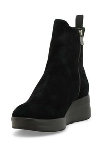 Stivale alla caviglia in suede nero con una finitura testurizzata, punta rotonda e zip laterale. Presenta una suola a zeppa spessa in un elegante nero opaco.