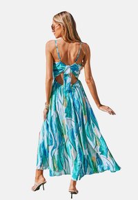 Maxi-jurk met een bloemenpatroon in tinten van blauw en groen. Gekruiste rug met een strikdetail, lichtgewicht stof en zijsplitten.
