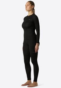 Svart långärmad topp och leggings i ett stretchigt, slätt material, med en diskret logotyp och en figurnära design för aktiv träning.