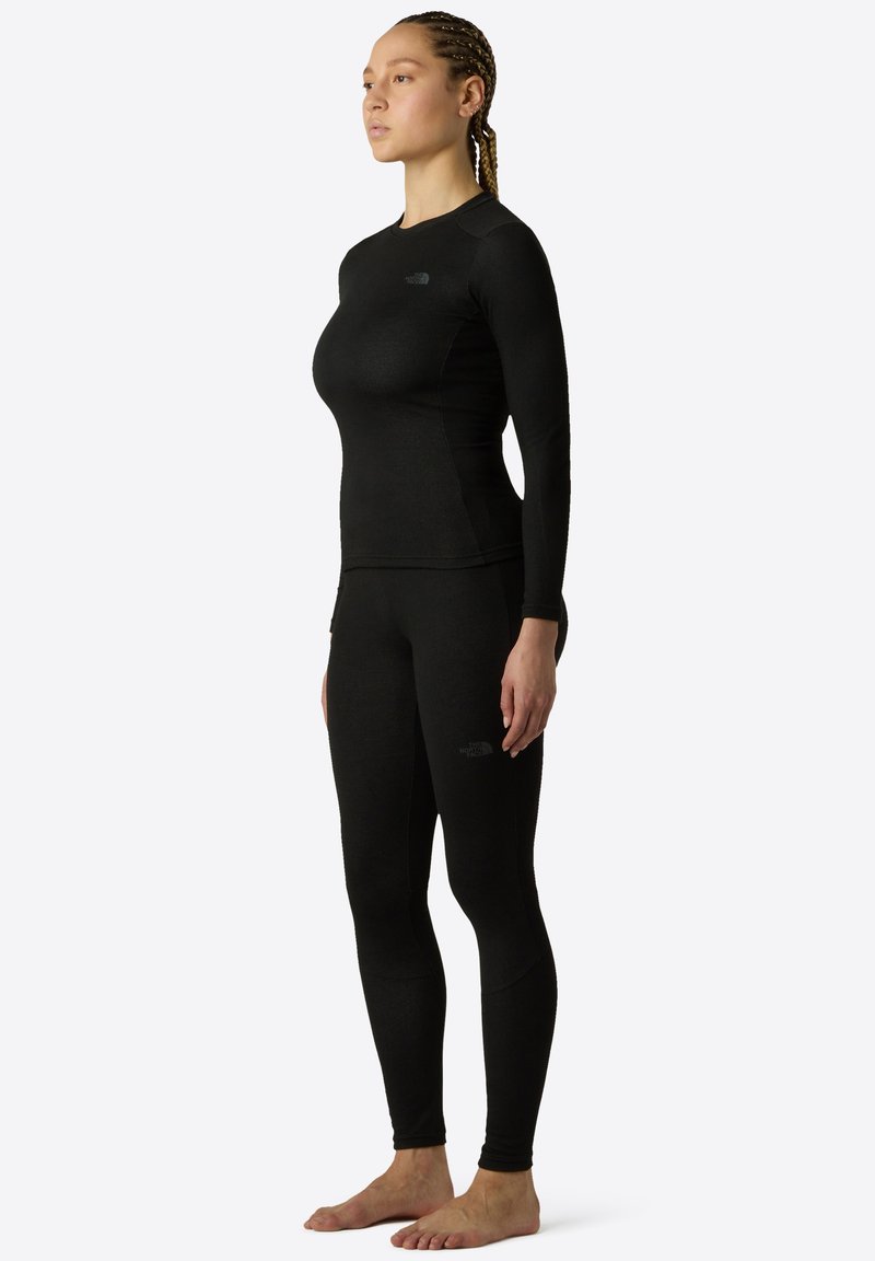 Svart långärmad topp och leggings i ett stretchigt, slätt material, med en diskret logotyp och en figurnära design för aktiv träning.