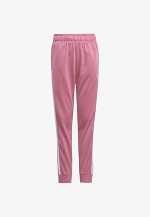 Pantalon de sport rose avec des bandes blanches sur les côtés, taille élastique, chevilles resserrées et petit logo Adidas blanc sur la cuisse gauche.