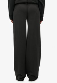 Sorte sweatpants med brede ben lavet af blød bomuldsblanding, med snøre i taljen og diskrete syningsdetaljer på bagsiden.