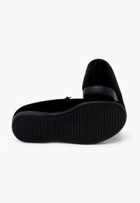 Schwarze Samt-Schlüpfschuhe mit runder Zehenpartie, kleinem Lederabsatz und strukturiertem Gummisohle mit horizontalen Rillen für besseren Halt.