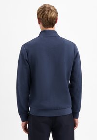 Marineblauwe, gestructureerde sweatshirt met een kraag, ribgebreide manchetten en onderrand. De achterkant toont een gladde stof en nauwkeurige stikseldetails.