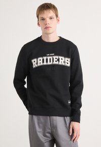 Sweatshirt preto com "RAIDERS" e "LAS VEGAS" estampados em branco. Gola redonda, punhos e barra canelados; apresenta etiqueta do logo na lateral.