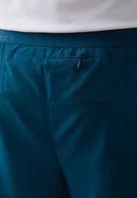 Τελαμινένια σπορ σορτς σε τιρκουάζ χρώμα με υφή, διαθέτοντας τσέπη με φερμουάρ στην πλάτη και επίπεδη μέση με ανάγλυφα σχέδια.