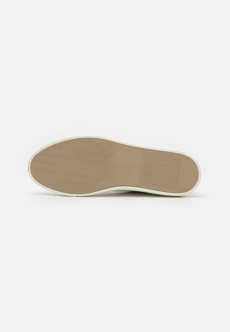Semelle de chaussure avec une surface en caoutchouc beige texturé, présentant des motifs en vagues et une bordure lisse, sur fond blanc.