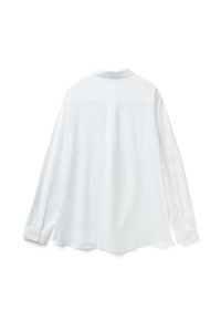 Bílá dlouhá košile s rukávy, má zádovou yoke a manžetami na jedno tlačítko, vyznačuje se hladkou texturou a mírně zaobleným lemem.