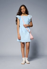 Light blue cotton dress with ruffled sleeves, paired with a patterned pink shoulder bag and white sandals with textured straps.