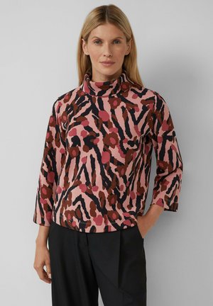 Langärmliges, pinkes Oberteil mit einem gemusterten Design, das dunkelbraune und schwarze Akzente aufweist. Der Kragen ist hoch und der Stoff scheint weich zu sein.