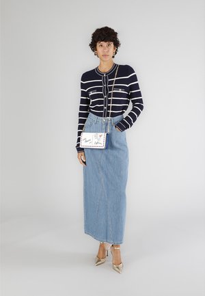 Cárdigan de punto a rayas en azul marino y blanco, falda maxi de mezclilla en azul claro, tacones dorados y un bolso cruzado blanco con detalles gráficos coloridos.