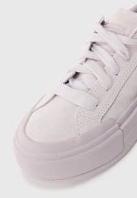 Light gray suede sneaker with a rounded toe, thick light purple rubber sole, and matching flat laces. Features subtle stitching details.