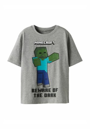 T-shirt gris à manches courtes avec un graphisme de personnage Minecraft. Le texte dit "MÉFIEZ-VOUS DU NOIR" en lettres noires en gras. Tissu doux.