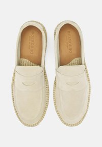 Beige ruskind slip-on sko med en mokkasinstil syning, vævet jutesål og glat tekstur; klassisk design med minimal detaljering.