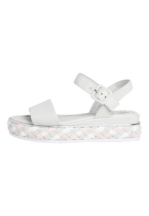White platform sandals featuring a wide strap, a buckle closure, and a braided multicolored sole with accents of pink, grey, and white.