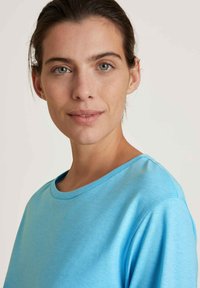 Lichtblauw t-shirt met korte mouwen en een ronde hals, gemaakt van gladde stof; heeft subtiele textuur en strakke lijnen.