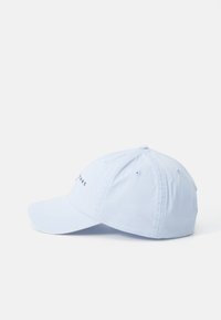 Lys blå baseballcaps med en buet skygge, laget av mykt stoff. Har brodert tekst foran og ventilasjonsluker.
