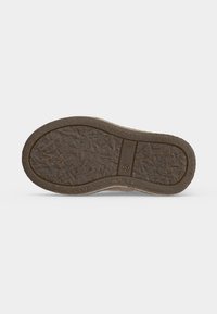 Semelle d'une chaussure marron avec une semelle texturée et une marque de taille 22 sur fond gris clair.