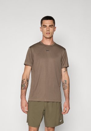 T-shirt marron à manches courtes avec un col rond et un logo discret sur la poitrine, associé à un short vert olive. Texture lisse.