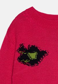 Fuchsia strikkegenser med ribbestrikket hals. Har et svart og grønt broderi på fronten. Myk tekstur, uformell stil.