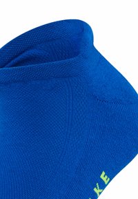Calcetín azul hasta el tobillo con un patrón de tejido texturizado. El borde superior es acanalado y hay un acento de logo amarillo en el costado.
