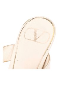 Gros plan d’une semelle intérieure beige en cuir d’une sandale présentant un logo Valentino délavé et des coutures visibles le long du bord.